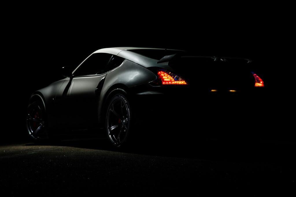 pexels-photo-919073-919073 A dramatic shot of a Nissan 370Z sports car illuminated in darkness with vibrant tail lights.